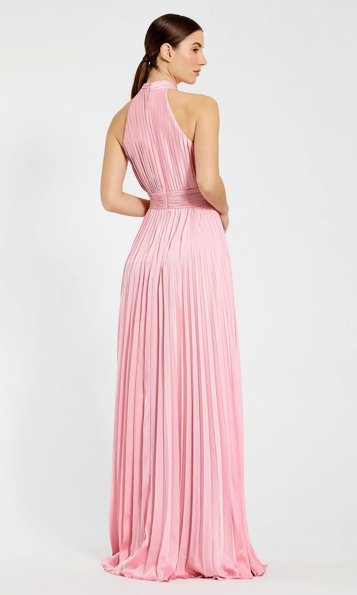 A woman stands with her back to the camera against a plain background, wearing the Long Pleated A-Line Formal Dress: Mac Duggal 26992—sleeveless, floor-length, and light pink.